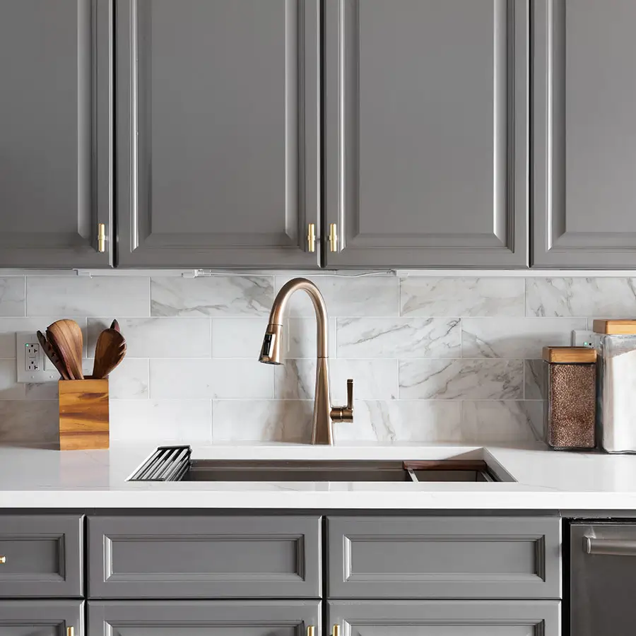 Kitchen with grey cabinets, white marble countertop and backsplash